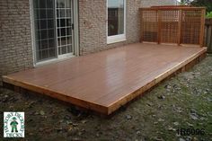 a wooden deck in front of a brick building with sliding glass doors on the side