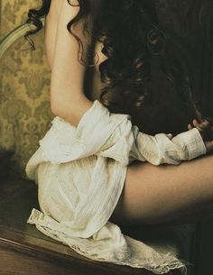 a woman sitting on top of a wooden table next to a mirror with her hands behind her head