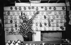 a man standing in front of a wall with lots of eggs on it and many other items around him