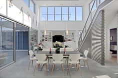 a dining room table and chairs in front of an open floor plan with high ceilings