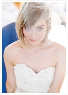 a woman in a wedding dress with a veil on her head is looking at the camera