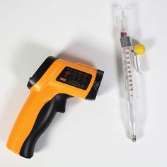 a thermometer next to a tube of liquid on a white surface with a needle