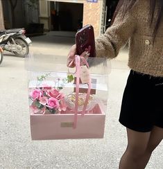 a woman is carrying a pink bag with flowers in it and holding a cell phone