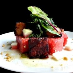 a white plate topped with slices of watermelon and cucumber garnish