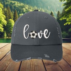 This hat is 100% cotton, soft and unstructured 6-panel low-fitting hat. One size fits most adult,Garment Washed Pigment Dyed Cotton Twill. Show your love for soccer with this stylish distressed baseball cap, featuring the word 'Love' with a soccer ball replacing the 'O'. Whether you're a player, a soccer mom, or just a fan of the beautiful game, this cap is a great way to express your passion. The distressed look gives it a trendy, vintage vibe, making it perfect for casual wear on game day or any day. Perfect for: Soccer fans, players, soccer moms, and gifting Whether you're at a soccer match or just running errands, this cap is the perfect accessory to show off your love for the sport. It also makes a great gift for soccer players, fans, or moms who are always cheering from the sidelines Adjustable Sports Fan Hat With Curved Visor, Distressed Casual Baseball Cap For Sports, Adjustable Gray Hat For Sports Events, Casual Gray Hat For Sports Events, Sports Fan Cap Hat One Size Fits Most, Sports Fan Cap One Size Fits Most, Cotton Sports Fan Hat With Curved Brim, Casual Adjustable Dad Hat For Sports Events, Soft-washed Baseball Cap, One Size Fits Most