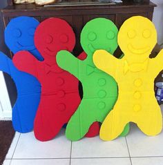 four wooden toy figures sitting next to each other in front of a table with bread on it