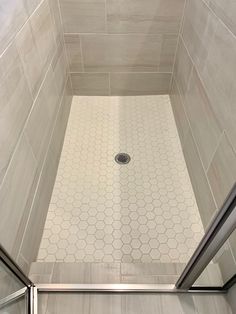 a bathroom with a shower stall and tiled flooring in the shower area is shown