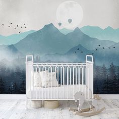 a baby crib in front of a wall mural with mountains and birds on it