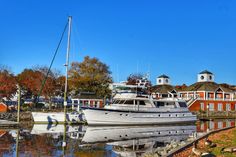 a boat is docked in the water next to some red brick buildings and trees with leaves on them