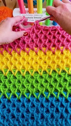 someone is crocheting together with colored yarns to make a rainbow afghan or shawl