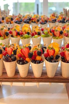 a table topped with lots of fruit cups filled with different types of berries and oranges