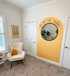 a white chair sitting in front of a mirror on the wall next to a door