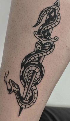 a black and white tattoo on the leg of a woman's legs, with a snake