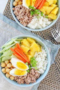 two bowls filled with rice, meat and veggies on top of a table