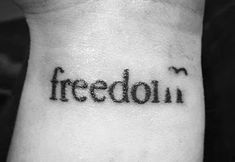 a black and white photo of a person's wrist with the word freedom written on it