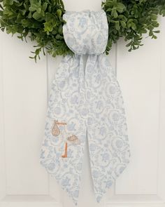 a blue and white scarf hanging on a door with greenery in the corner next to it