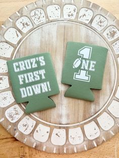 two decorated cookies sitting on top of a wooden plate with the words cruz's first down