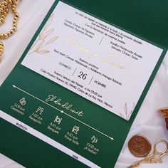 a green and white wedding card with gold foil on it, surrounded by other items