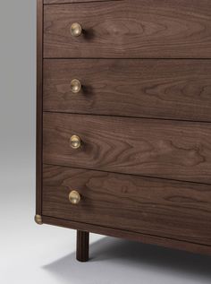 the chest of drawers is made out of wood and has brass knobs on each drawer