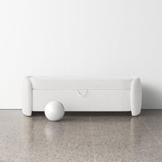 a white couch sitting on top of a floor next to a wall with a ball