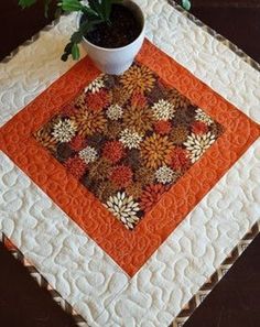 a potted plant sitting on top of an orange and white quilted placemat