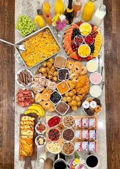 a table filled with lots of food on top of a wooden floor next to drinks