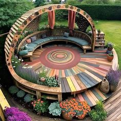 a circular wooden bench sitting in the middle of a lush green field with lots of flowers