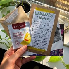 a person holding up a packet of red seal's world next to a potted plant