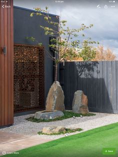 two large rocks sitting in the middle of a small garden area with grass and trees