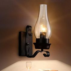 a light that is on the wall next to a wine glass and some books in front of it