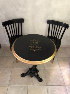 two black and gold chairs sitting at a table with the words cafe de paris on it