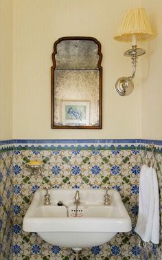 a white sink sitting under a bathroom mirror next to a wall mounted faucet