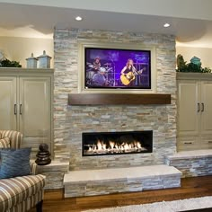 a living room filled with furniture and a flat screen tv mounted on the wall above a fire place