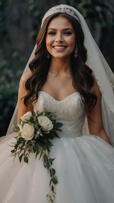 a woman in a wedding dress holding a bouquet and smiling at the camera while wearing a bridal gown