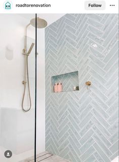 the bathroom is decorated in white and gray herringbone tile, along with a glass shower head