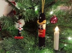 a christmas tree with ornaments hanging from it's branches and a lit candle in the foreground