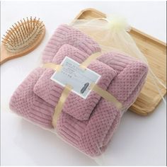 a pile of pink towels sitting on top of a wooden tray next to a brush