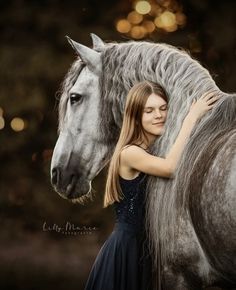 a woman is hugging a horse in front of some blurry lights and boke