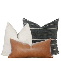 three pillows with different colors and patterns on them, one is black, the other is white