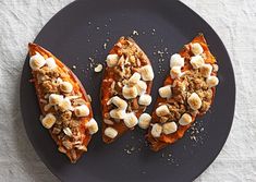 three slices of pizza with toppings on a black plate next to a white cloth