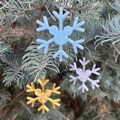 three snowflake ornaments hanging from a pine tree