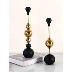 two black and gold candlesticks sitting on top of a book