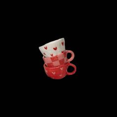 two red cups with hearts on them sitting side by side in front of a black background