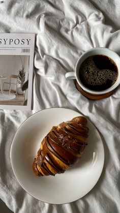 a plate with some food on it next to a cup of coffee and a book