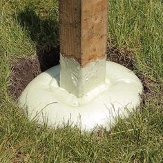 a wooden post sticking out of the ground next to a white object in some grass