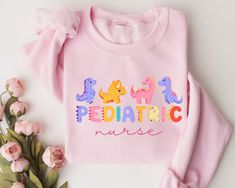 a pink shirt with the words pediatric nurse on it next to some flowers and leaves