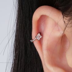 a woman's ear is shown with a single diamond in the middle and a small flower at the end