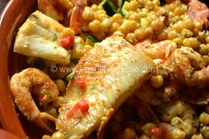 a bowl filled with shrimp, corn and other food on top of a wooden table