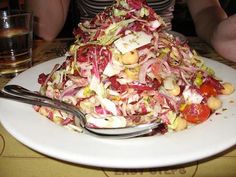 a large pile of food sitting on top of a white plate next to a fork