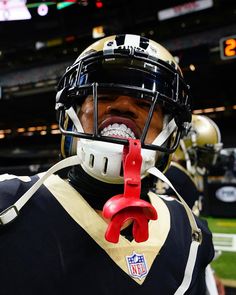 a football player wearing a helmet and holding a pair of red handled pliers in his mouth